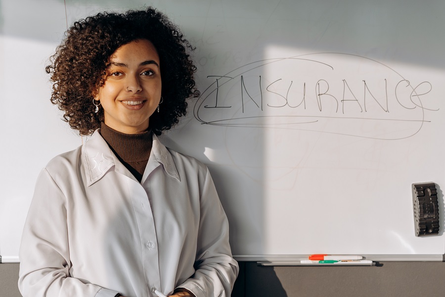 donna con grembiule davanti ad una lavagna con scritta insurance